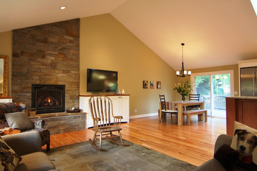 Large elegant open concept medium tone wood floor living room photo in Portland with beige walls, a standard fireplace, a stone fireplace and a wall-mounted tv