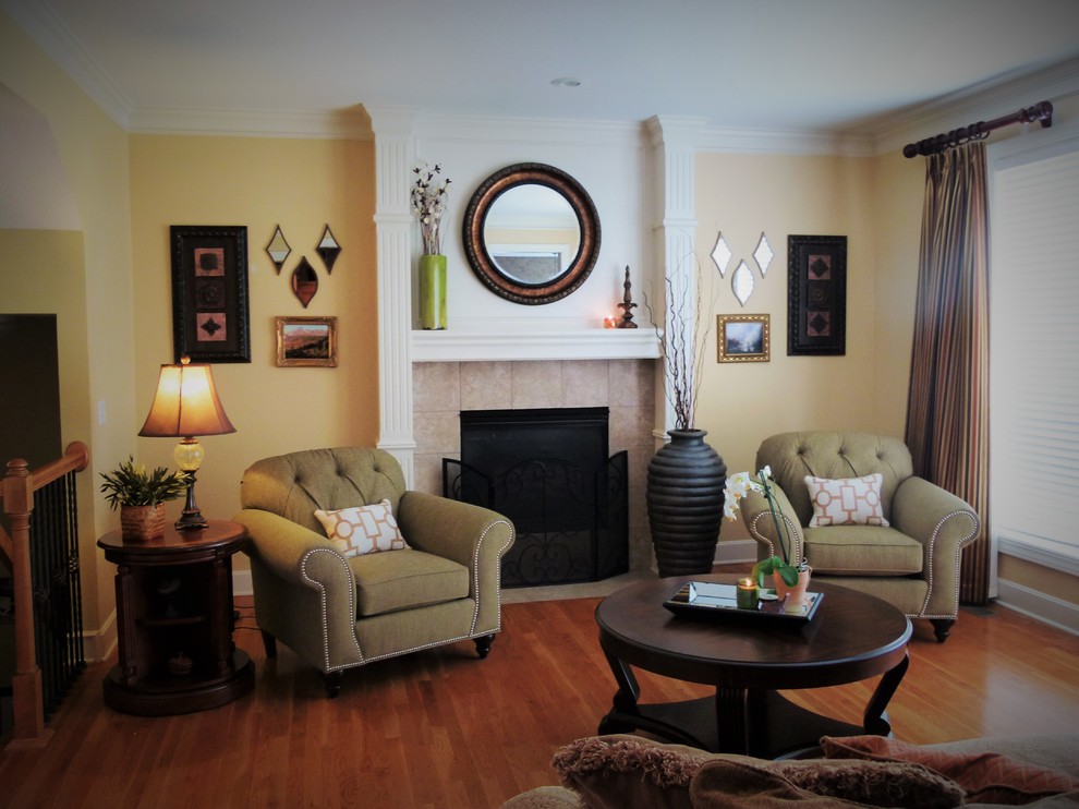 Fernseherloses, Offenes, Mittelgroßes Klassisches Wohnzimmer mit gelber Wandfarbe, braunem Holzboden, Kamin und gefliester Kaminumrandung in Kansas City