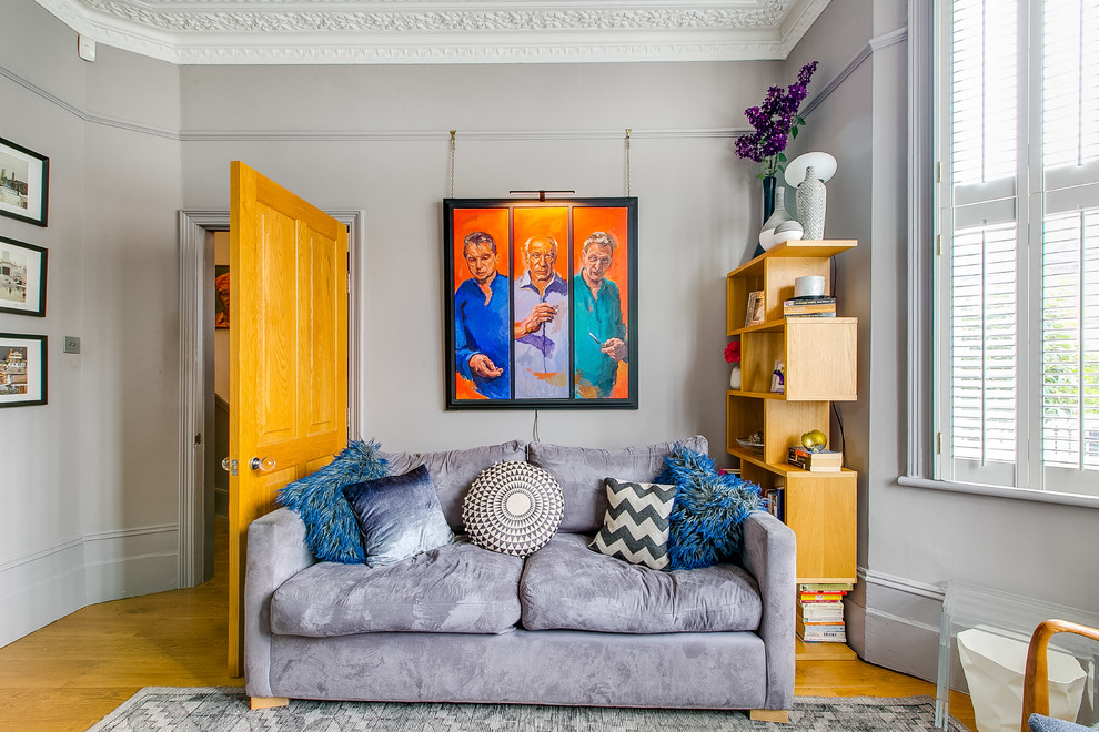 Eclectic enclosed living room in London with grey walls, medium hardwood flooring and beige floors.