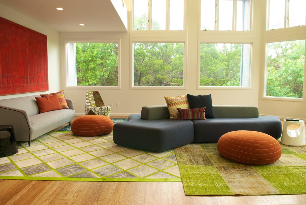 This is an example of a large modern open plan living room in Austin with white walls and light hardwood flooring.