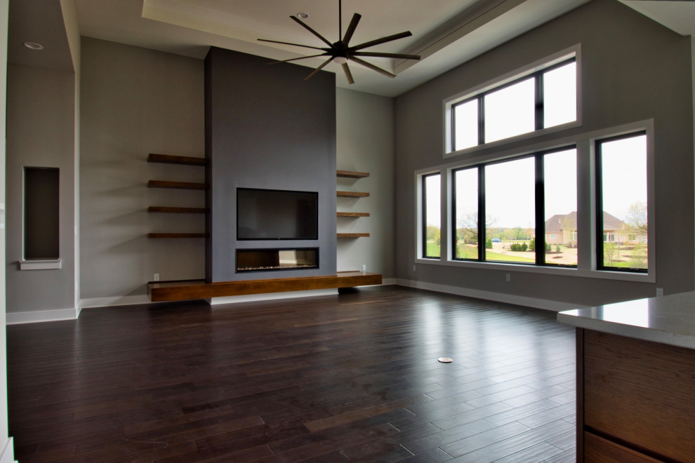 Living room - large modern open concept dark wood floor, brown floor and tray ceiling living room idea in Milwaukee with gray walls, a ribbon fireplace, a plaster fireplace and a wall-mounted tv