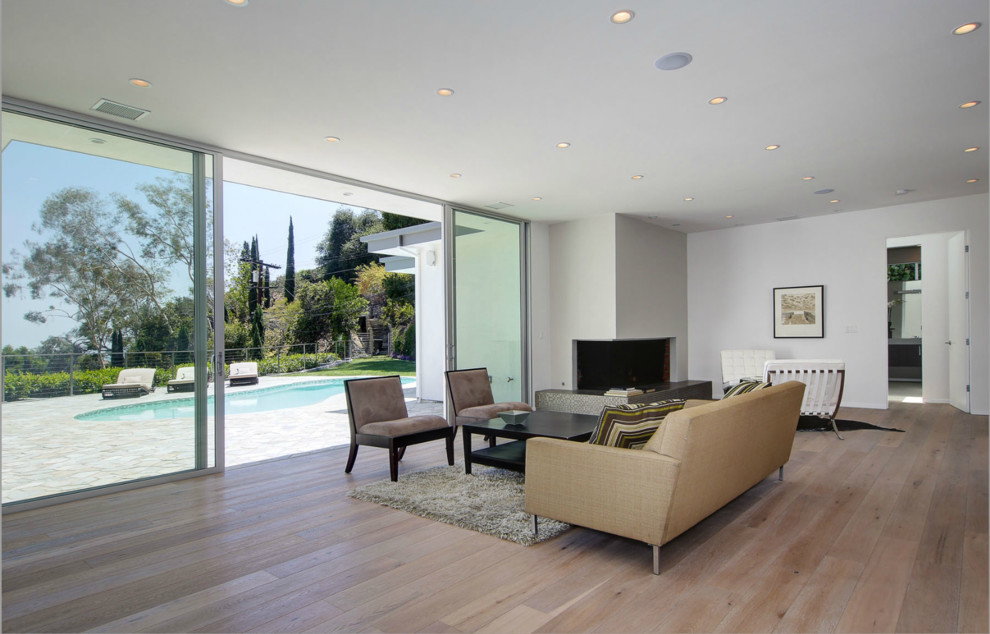 Huge 1960s open concept light wood floor living room photo in Los Angeles with white walls and a corner fireplace
