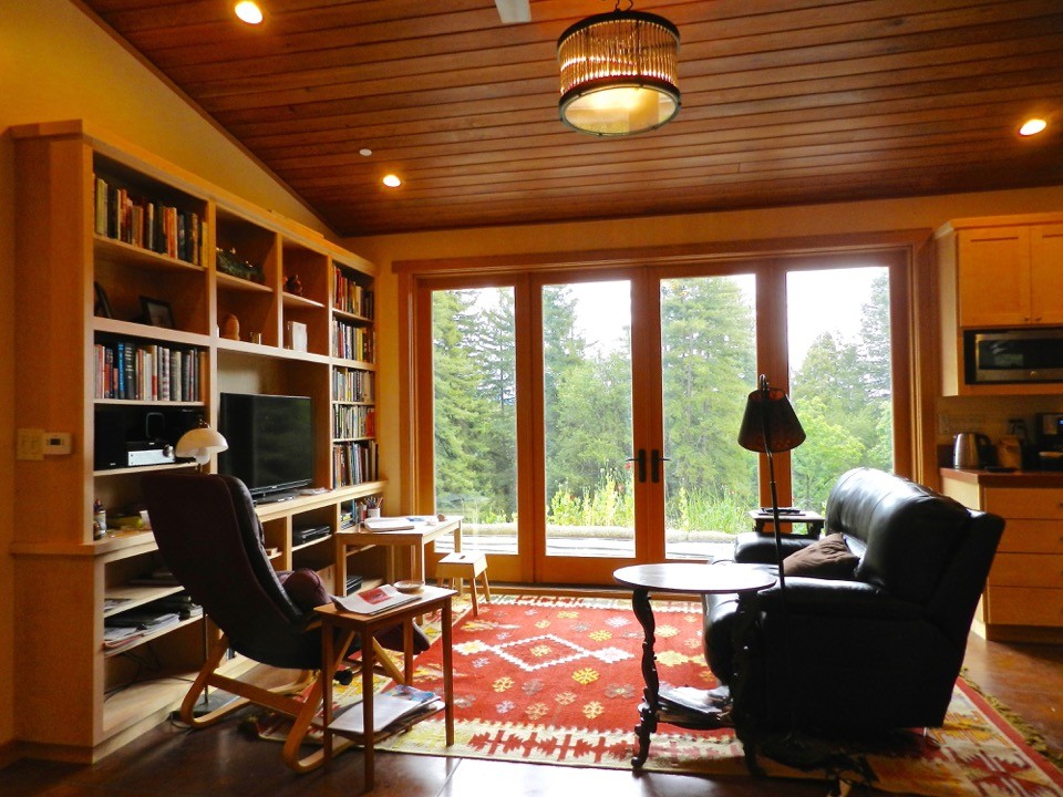 Foto di uno studio boho chic di medie dimensioni con libreria, pareti beige, pavimento in cemento e stufa a legna