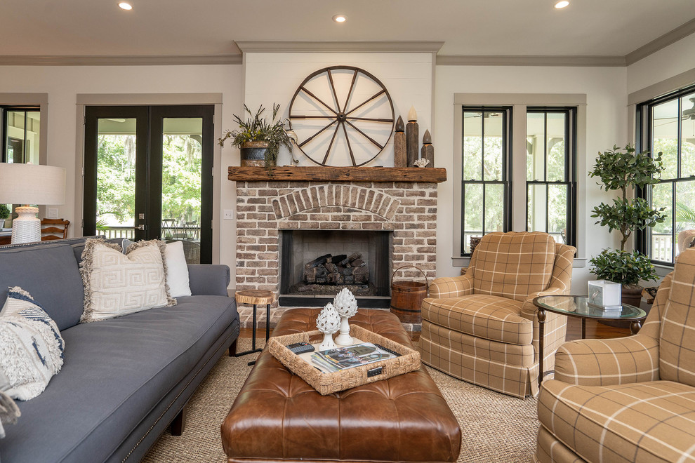 This is an example of a farmhouse open plan living room in Atlanta with white walls, medium hardwood flooring, a standard fireplace, a brick fireplace surround and brown floors.