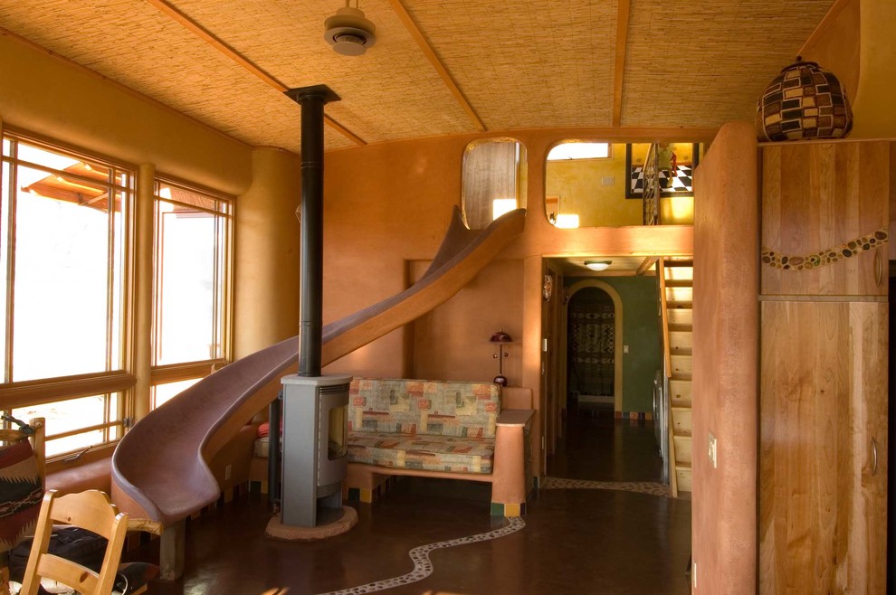Immagine di un piccolo soggiorno bohémian aperto con pareti arancioni, stufa a legna, nessuna TV e pavimento marrone