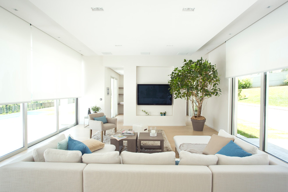 Immagine di un soggiorno moderno di medie dimensioni con pareti bianche e TV a parete