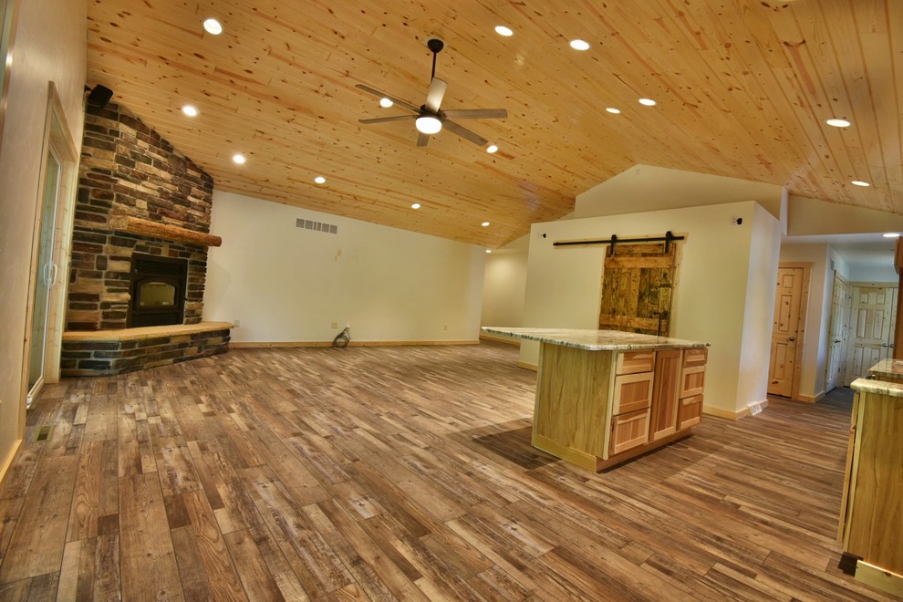 Ejemplo de salón abierto rural grande con paredes blancas, suelo de madera en tonos medios, chimenea de esquina, marco de chimenea de ladrillo y suelo marrón