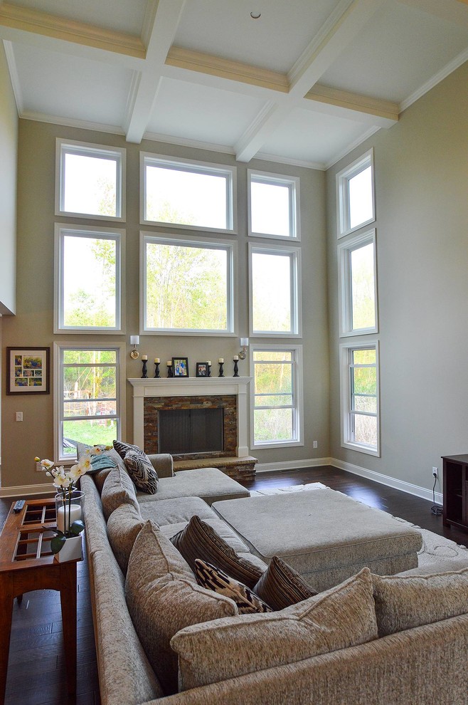 Offenes Klassisches Wohnzimmer mit beiger Wandfarbe, braunem Holzboden, Kamin, Kaminumrandung aus Holz und TV-Wand in Cleveland