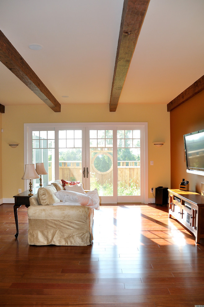 Idee per un soggiorno bohémian con pareti gialle, pavimento in legno massello medio e TV a parete