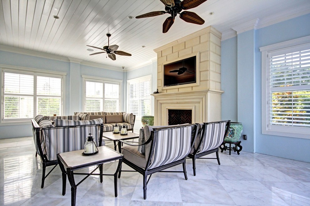 マイアミにある高級な中くらいなトラディショナルスタイルのおしゃれな独立型リビング (青い壁、大理石の床、標準型暖炉、漆喰の暖炉まわり、壁掛け型テレビ、ベージュの床) の写真