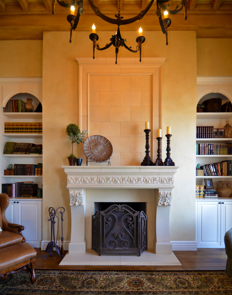Ejemplo de biblioteca en casa mediterránea con paredes beige, suelo de madera en tonos medios y todas las chimeneas
