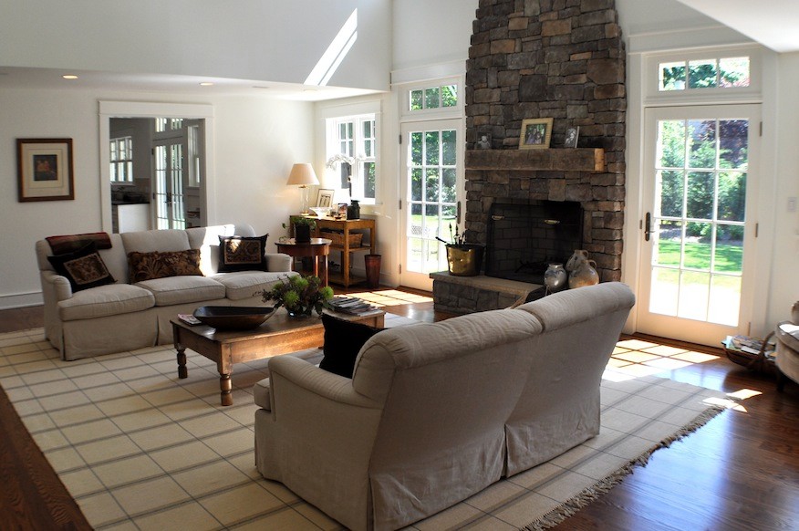 Mittelgroßes, Fernseherloses Klassisches Wohnzimmer mit weißer Wandfarbe, braunem Holzboden, Kamin und Kaminumrandung aus Stein in New York