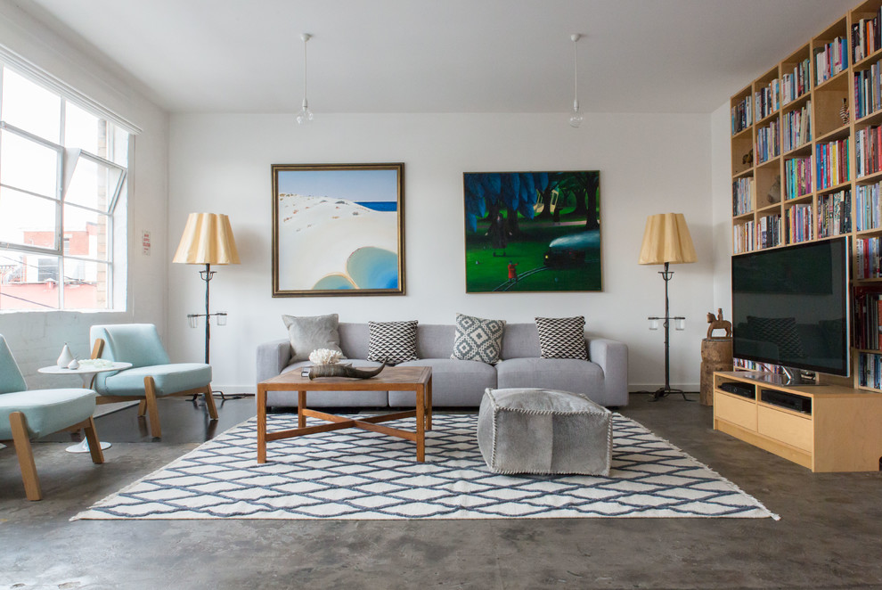 Idee per un soggiorno scandinavo di medie dimensioni e aperto con pareti bianche, pavimento in cemento, libreria e TV autoportante