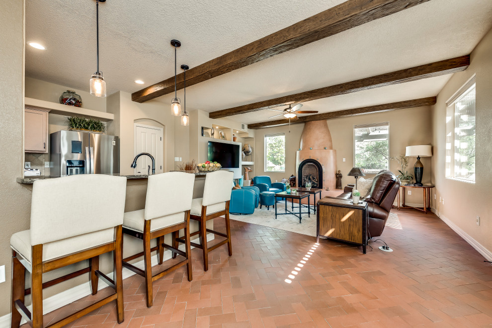 Kleines, Offenes Mediterranes Wohnzimmer mit brauner Wandfarbe, Backsteinboden, verputzter Kaminumrandung, Multimediawand und rotem Boden in Albuquerque
