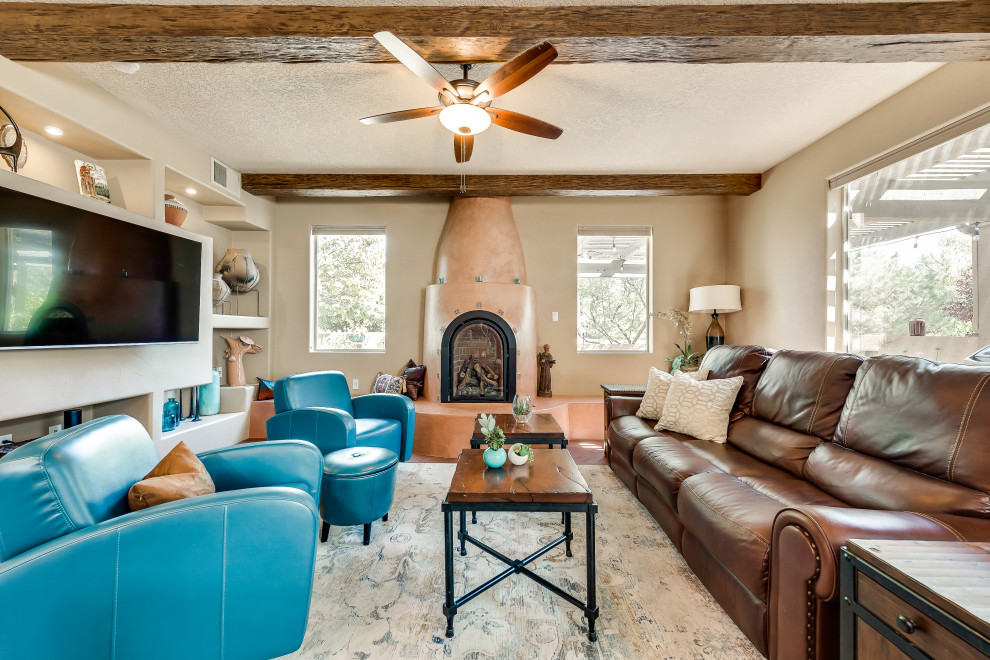 Idée de décoration pour un petit salon sud-ouest américain ouvert avec un mur marron, un sol en brique, un manteau de cheminée en plâtre, un téléviseur encastré et un sol rouge.