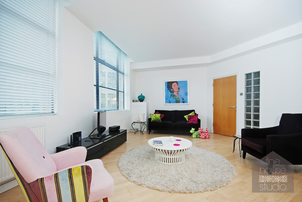 Photo of a large contemporary open plan living room in London with white walls, light hardwood flooring and a freestanding tv.