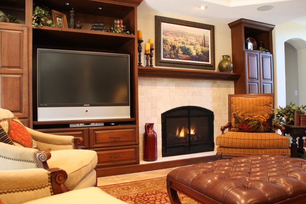 デンバーにある中くらいな地中海スタイルのおしゃれな応接間 (標準型暖炉、タイルの暖炉まわり、ベージュの壁、トラバーチンの床、据え置き型テレビ、ベージュの床) の写真