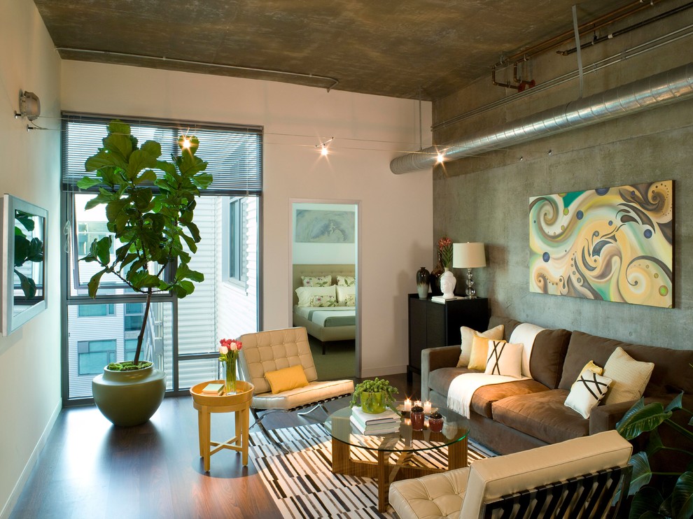 На фото: гостиная комната среднего размера в стиле лофт с телевизором на стене и коричневым диваном с