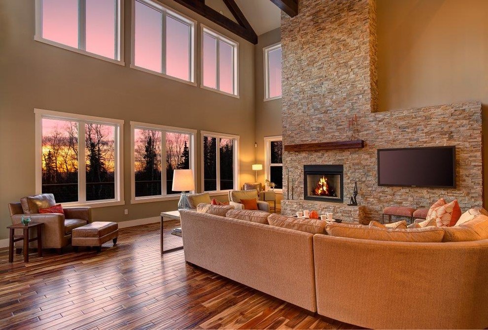 Großes, Offenes Rustikales Wohnzimmer mit beiger Wandfarbe, braunem Holzboden, Kamin, TV-Wand und Kaminumrandung aus Stein in Sonstige