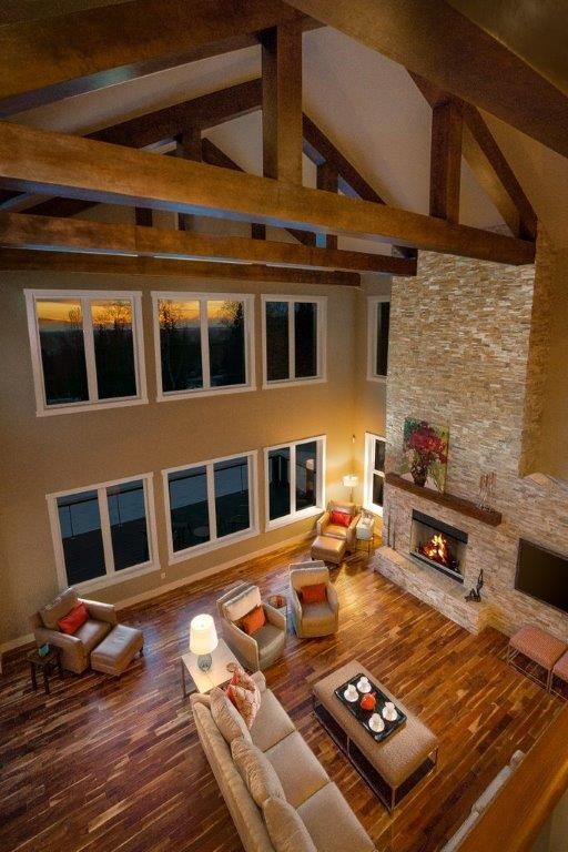 Modelo de salón tipo loft rústico grande con paredes beige, suelo de madera en tonos medios, todas las chimeneas, marco de chimenea de ladrillo y televisor colgado en la pared