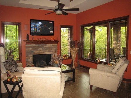 Esempio di un soggiorno moderno di medie dimensioni e chiuso con pareti arancioni, moquette, camino classico, cornice del camino in pietra e TV a parete