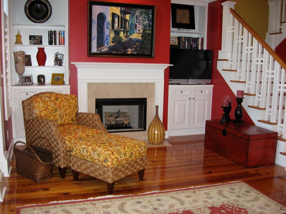 Inspiration pour un petit salon bohème avec un mur rouge, un sol en bois brun, une cheminée standard, un manteau de cheminée en pierre, un téléviseur indépendant et un sol marron.