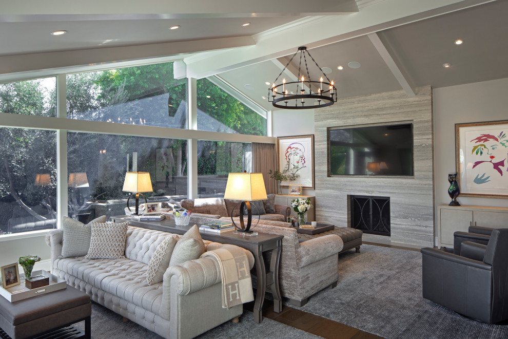 This is an example of a classic open plan living room in Los Angeles with grey walls, medium hardwood flooring, a standard fireplace, a wall mounted tv, brown floors, exposed beams and a vaulted ceiling.