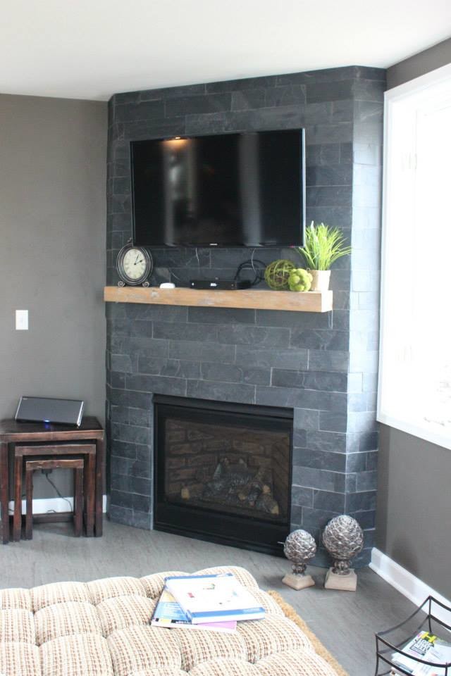Réalisation d'un salon tradition de taille moyenne avec un mur gris, une cheminée standard, un manteau de cheminée en brique et un téléviseur fixé au mur.