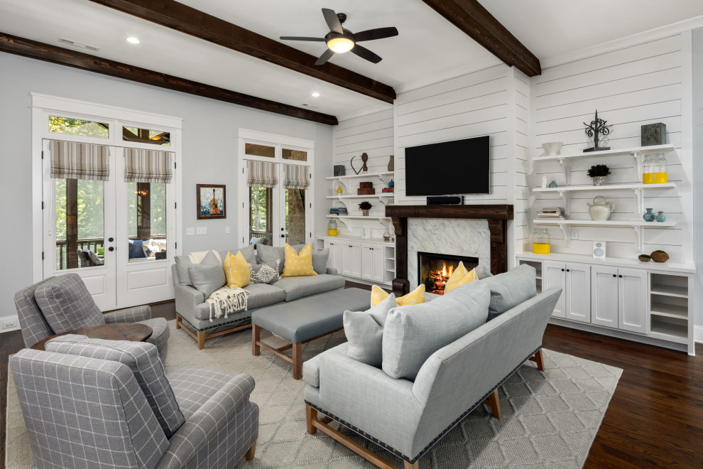 Classic open plan living room in Nashville with white walls, dark hardwood flooring, a standard fireplace, a stone fireplace surround, a wall mounted tv and brown floors.