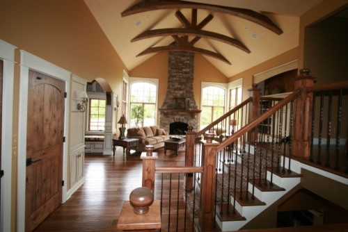 Mittelgroßes, Offenes Klassisches Wohnzimmer mit oranger Wandfarbe, dunklem Holzboden, Kamin und Kaminumrandung aus Stein in Grand Rapids