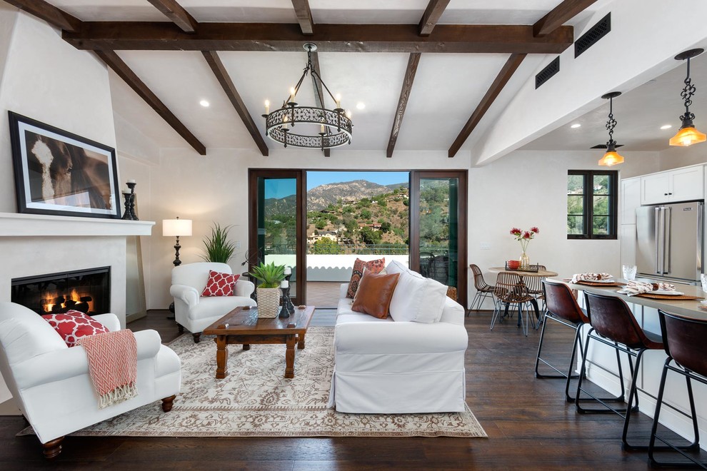 Repräsentatives, Offenes Mediterranes Wohnzimmer mit weißer Wandfarbe, dunklem Holzboden und Kamin in Santa Barbara