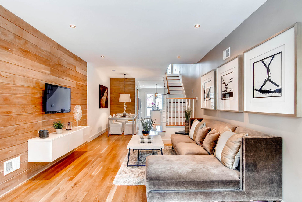 Modelo de salón para visitas abierto clásico renovado con paredes grises, suelo de madera en tonos medios y televisor colgado en la pared