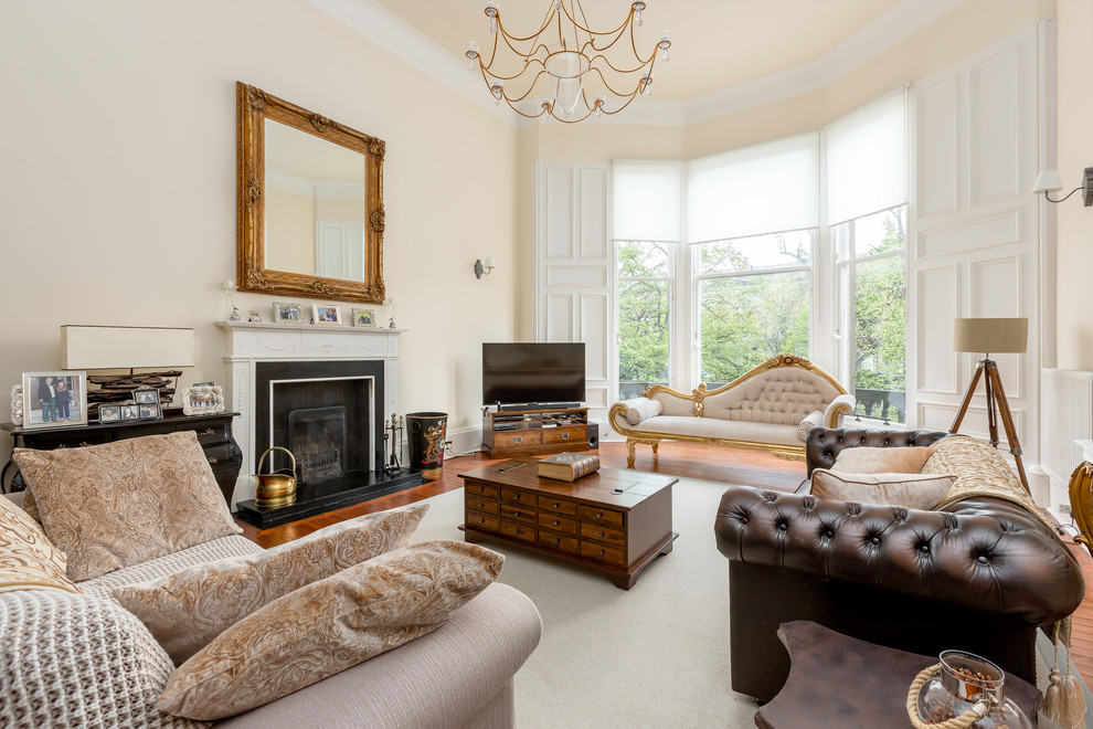 Photo of an eclectic enclosed living room in Other with orange walls, a standard fireplace, a freestanding tv and brown floors.