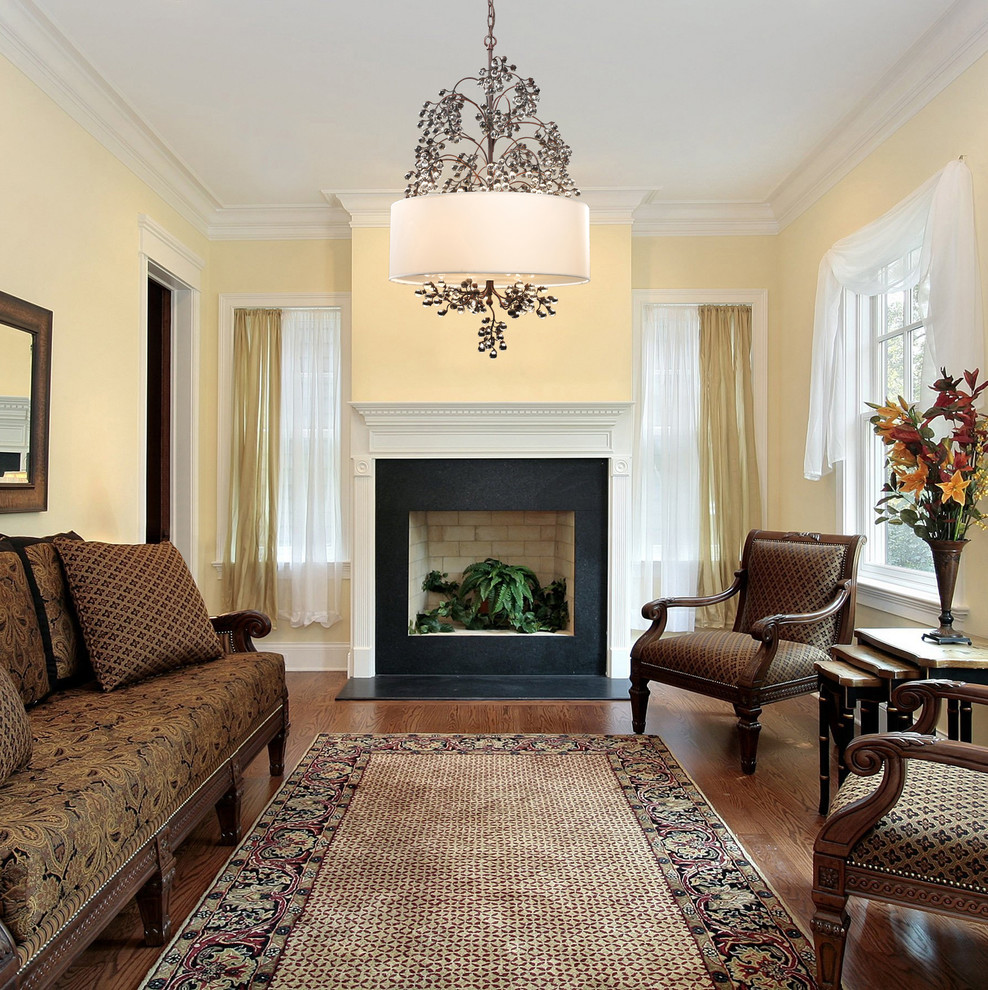 Ejemplo de salón para visitas clásico con paredes amarillas, suelo de madera en tonos medios y todas las chimeneas