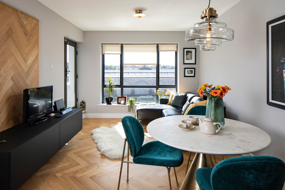 This is an example of a small modern formal open plan living room in Dublin with grey walls, medium hardwood flooring, beige floors and a freestanding tv.