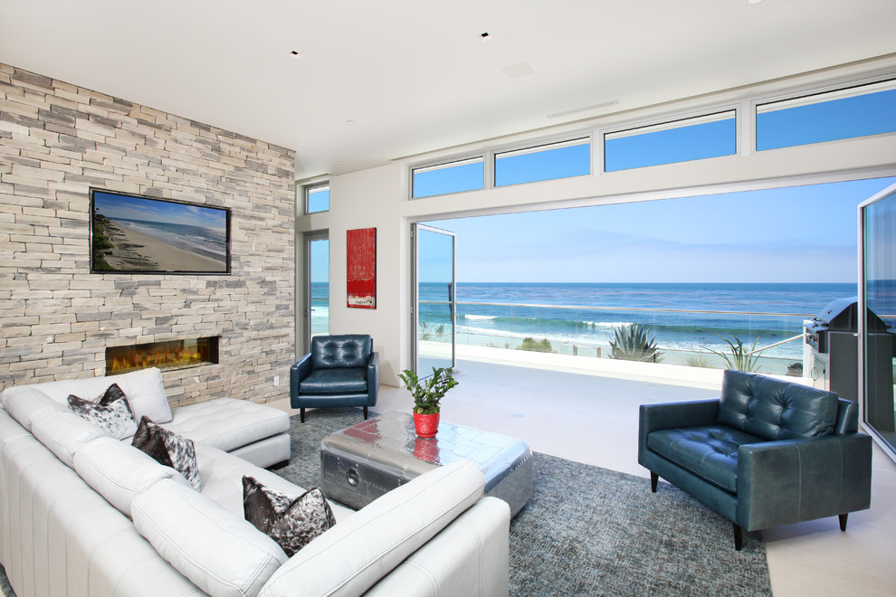 Идея дизайна: гостиная комната в морском стиле с горизонтальным камином, фасадом камина из камня, телевизором на стене и белым полом