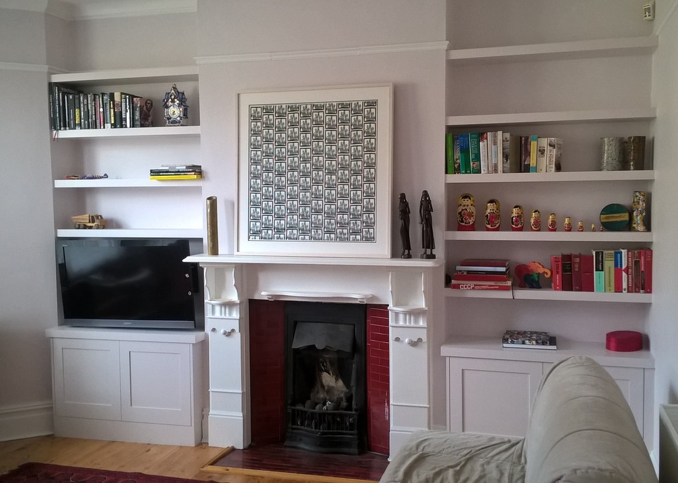 ロンドンにあるお手頃価格の小さなコンテンポラリースタイルのおしゃれな独立型リビング (白い壁、淡色無垢フローリング、標準型暖炉、金属の暖炉まわり、壁掛け型テレビ) の写真