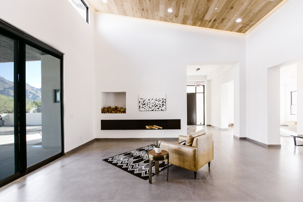 Источник вдохновения для домашнего уюта: большая открытая гостиная комната в скандинавском стиле с белыми стенами, полом из керамогранита, горизонтальным камином, фасадом камина из металла, телевизором на стене и серым полом