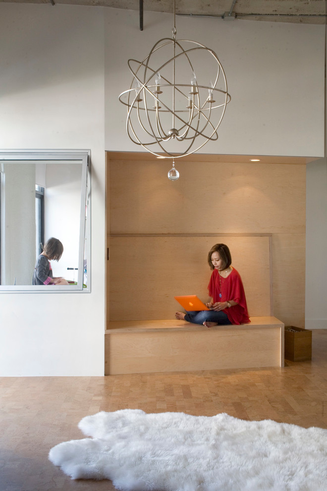 Imagen de biblioteca en casa tipo loft moderna de tamaño medio sin chimenea con paredes blancas, suelo de corcho y pared multimedia