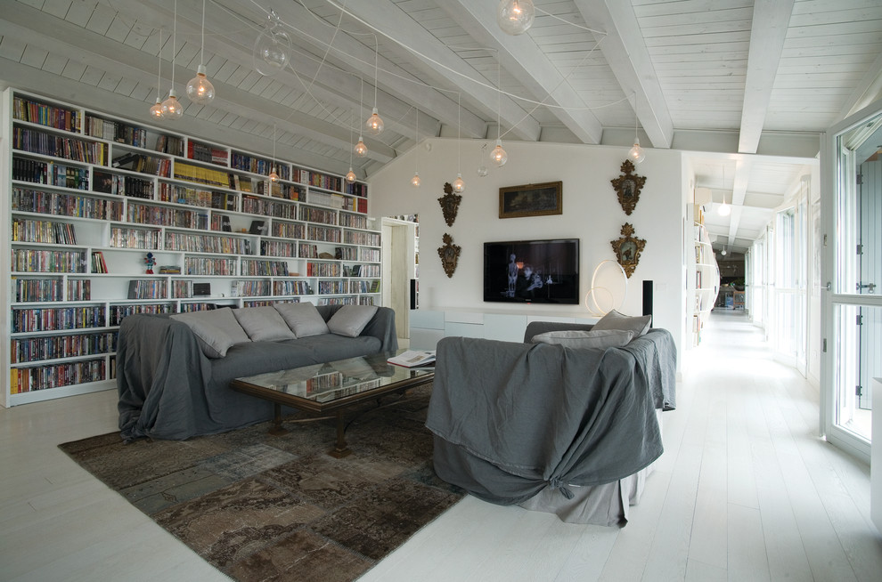 Immagine di un grande soggiorno design con libreria, pareti bianche, pavimento in legno verniciato e TV a parete