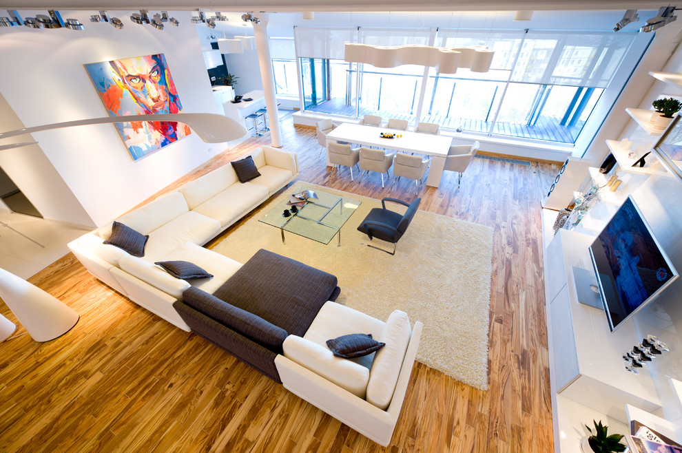 Foto de salón para visitas tipo loft contemporáneo grande con paredes blancas, suelo de madera clara y televisor independiente
