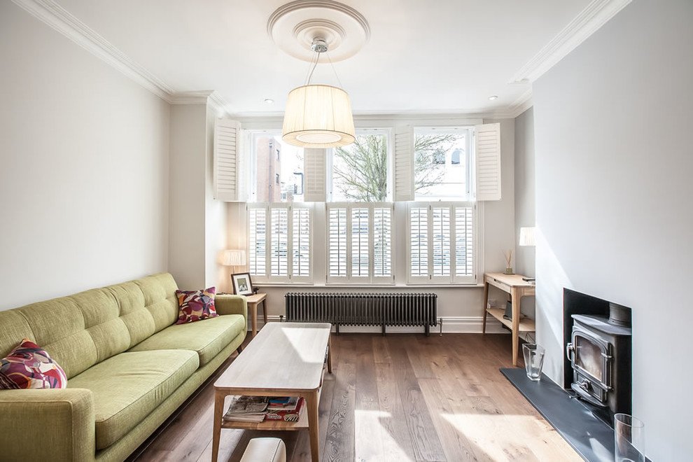 Fernseherloses Klassisches Wohnzimmer mit braunem Holzboden, Kaminofen und grauer Wandfarbe in Sonstige