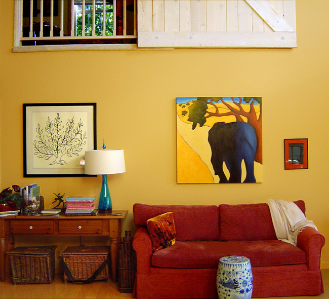 Immagine di un grande soggiorno country stile loft con pareti gialle, stufa a legna, cornice del camino piastrellata, libreria, nessuna TV e parquet chiaro