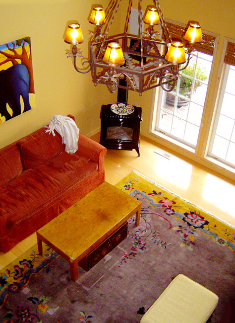 Foto de salón tipo loft de estilo americano grande con paredes amarillas, estufa de leña, marco de chimenea de madera y suelo de madera clara