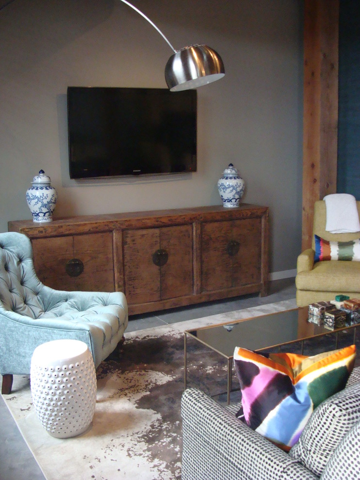 Foto di un soggiorno bohémian di medie dimensioni e stile loft con pareti grigie, pavimento in cemento e TV a parete