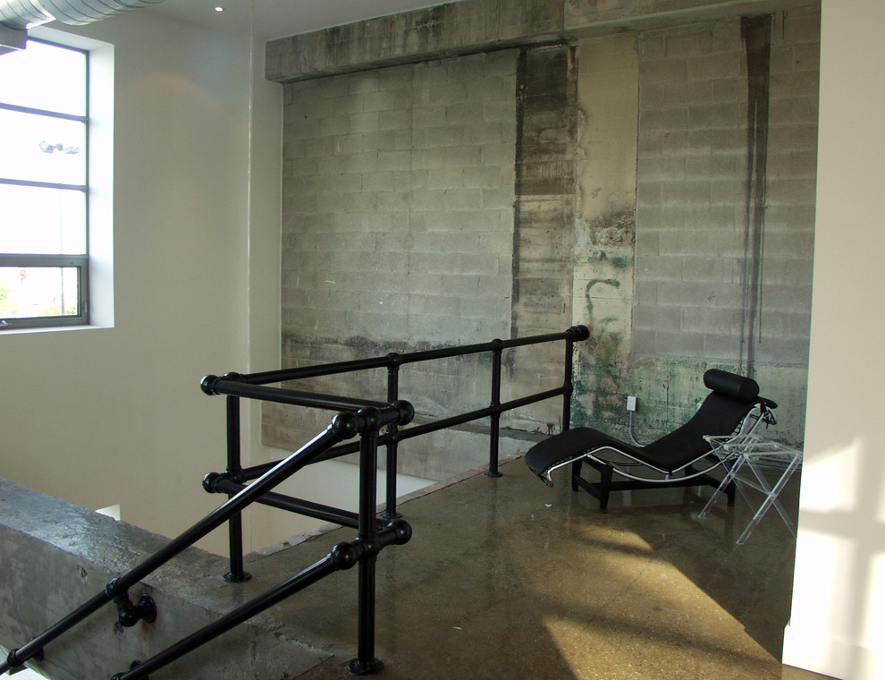 Aménagement d'un salon industriel avec sol en béton ciré et un escalier.