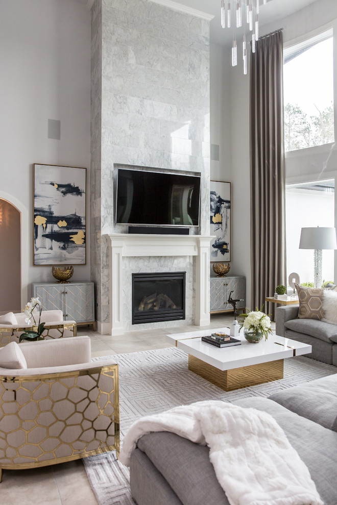 На фото: гостиная комната:: освещение в стиле неоклассика (современная классика) с серыми стенами, стандартным камином, фасадом камина из камня, телевизором на стене и бежевым полом