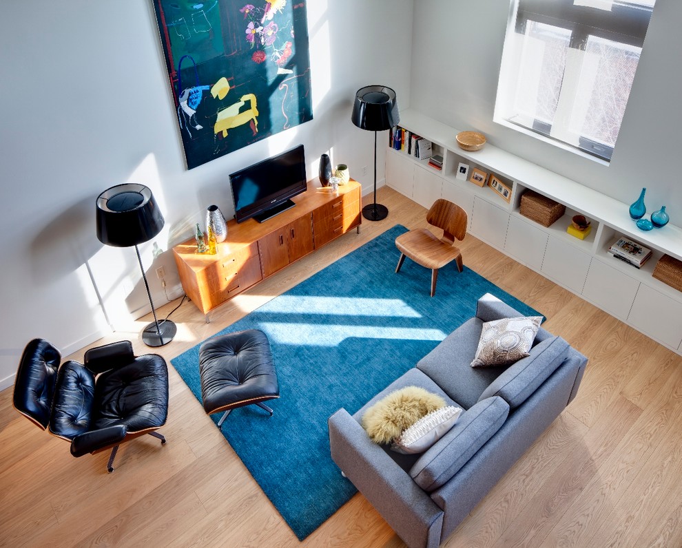 Medium sized modern open plan living room in Toronto with white walls, light hardwood flooring and a freestanding tv.