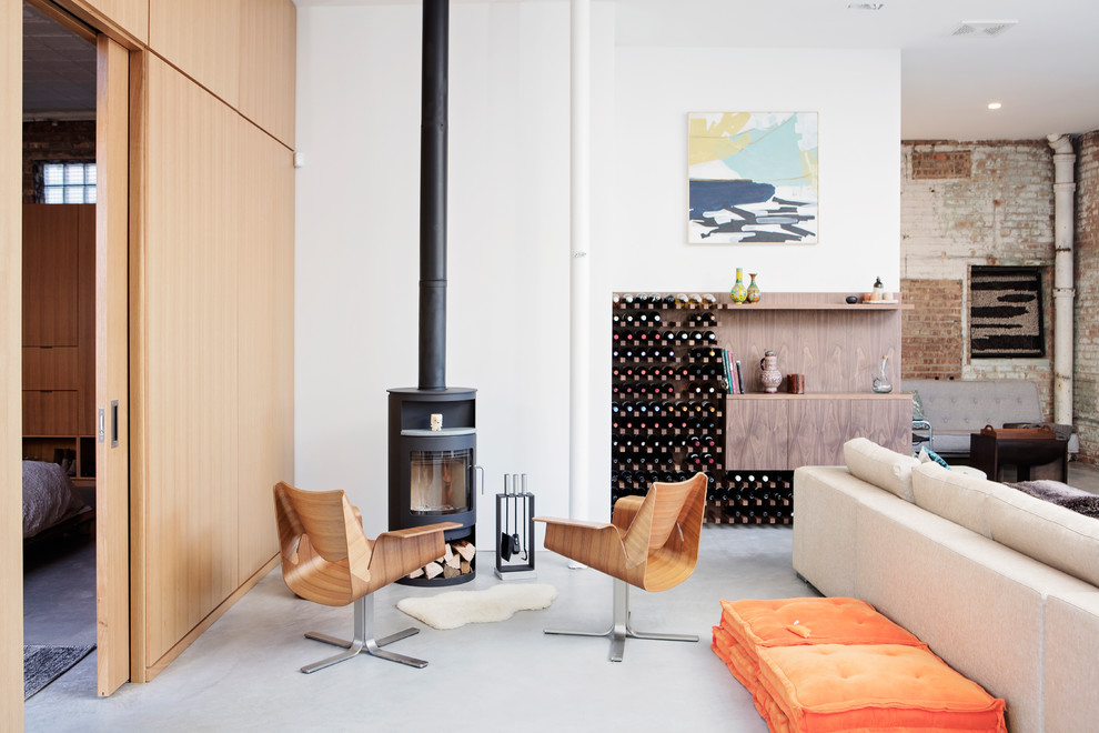 Aménagement d'un salon contemporain de taille moyenne et ouvert avec un mur blanc, un poêle à bois, un manteau de cheminée en métal, sol en béton ciré et un sol gris.