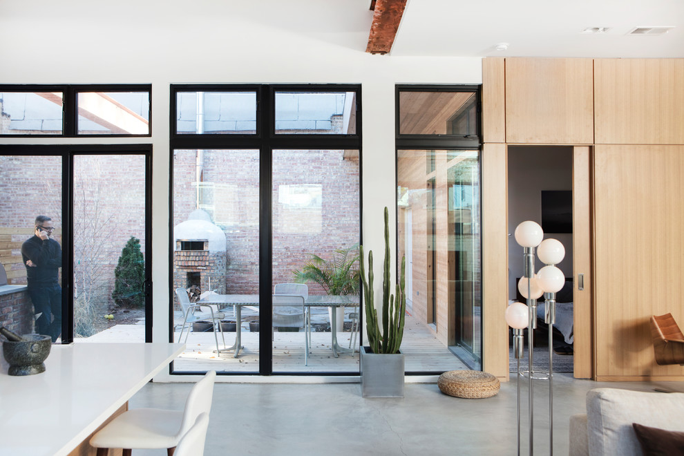 Esempio di un soggiorno minimalista di medie dimensioni e aperto con pareti bianche, pavimento in cemento, stufa a legna, cornice del camino in metallo e pavimento grigio